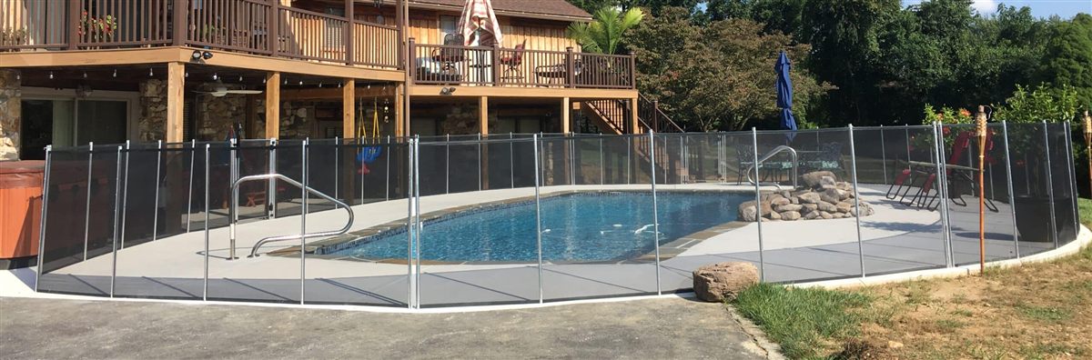 A removable Merlin mesh safety fence enclosing a backyard in-ground pool